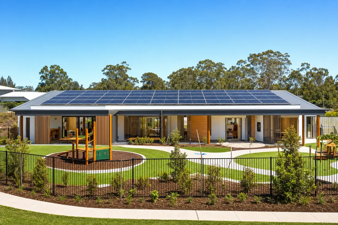 A single-storey childcare building with solar panels across the roof and a fenced yard alongside