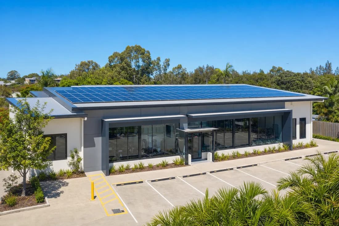A gym building with a wide roof carrying a full solar array