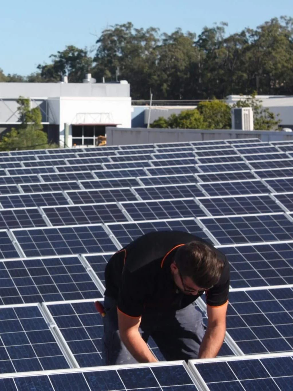 An installer fixing solar panels to the roof of a commercial building